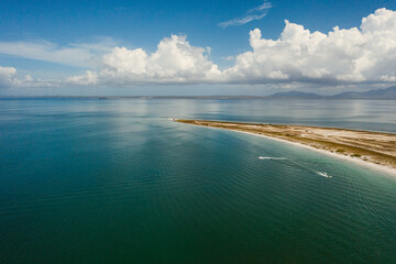Fototapeta na wymiar Vista aérea de orilla de playa en el caribe bajo el cielo azul y grandes nubes blancas
