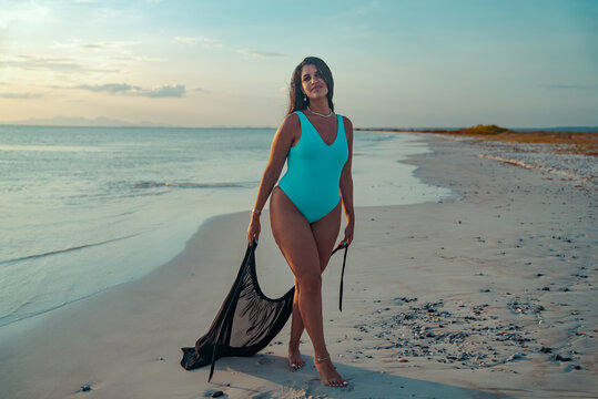 Mujer latina modelando en la playa de la isla de margarita en Venezuela sosteniendo su vestido