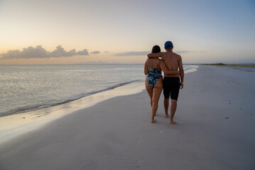 Pareja latina caminando por orilla de playa en isla de margarita Venezuela mientras ven el...