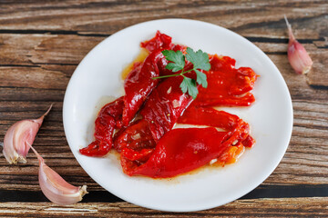 Peeled peppers, salad from grill baked marinated vegetable pepper, grilled fresh, portion on plate, ready to eat meal snack on the table, top view, food background, rustic