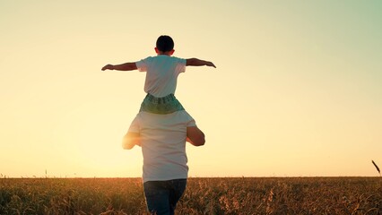 Little kid superhero imagines soaring through sky at sunset. Loving father runs with playful son on...