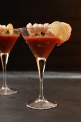Tasty shrimp cocktail with sauce in glasses and lemon on grey table, closeup