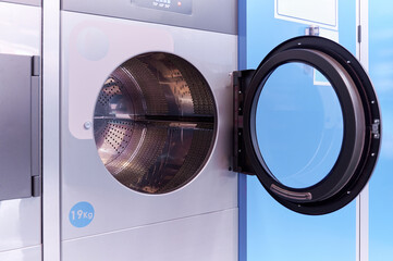 High capacity industrial dryer machine with the door opened inside a laundry service bussiness....