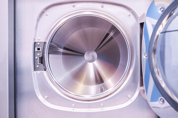 Interior of an industrial washing machine with the door open revealing the washing drum. Laundry service concept.
