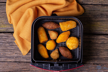 delicious Brazilian snacks made inside the airfryer basket view from above on a rustic wooden table with selective focus