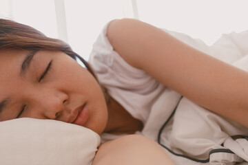 Close up of lazy Asian woman just wake up but not going to get up from the bed.