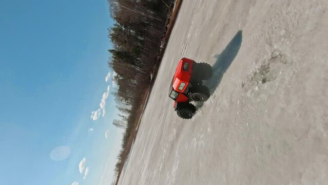 Icy Terrain Dominator. A car with big wheels on a frozen lake. Vertical 9x16 FPV Aerial Drone shot