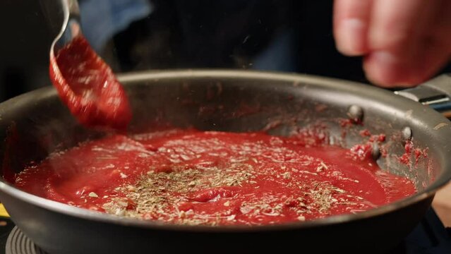 Cooking tomato sauce classic homemade Italian tomato sauce with basil for pasta and pizza in the pan. Chef cooking traditional Italian food.