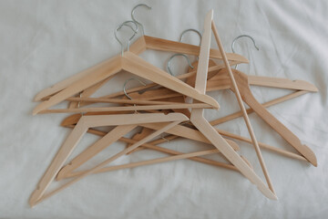 Piles of wooden clothes hangers left not arranged in order on white cloth. 