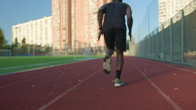 Low start position back view runner African American man guy sportsman preparing ready starting on running track male runner jogger run marathon active sport training outdoors jogging at city sunlight