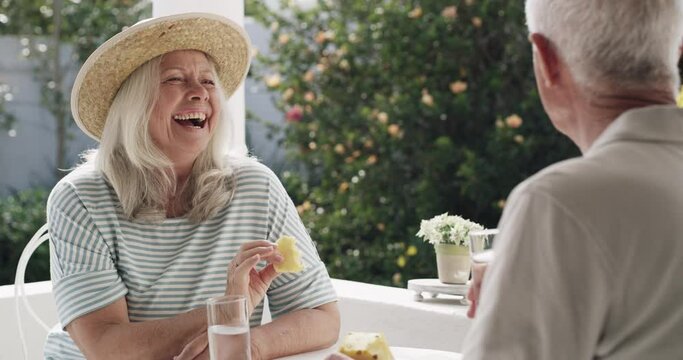 Happy woman, funny and senior couple eating pineapple together, relax and listening to conversation story. Happiness, love and talking elderly wife, old man or marriage people bond on outdoor porch