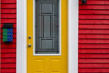 The exterior of a vibrant red wooden wall of a country style house with a colorful yellow metal...
