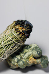 Burning California White Sage and Sweetgrass Ceremonial Herb Bundle Resting on Rough Natural Formation of Green Prehnite Crystal Gemstone Mineral Healing Energy Crystal Cleansing Spiritual 