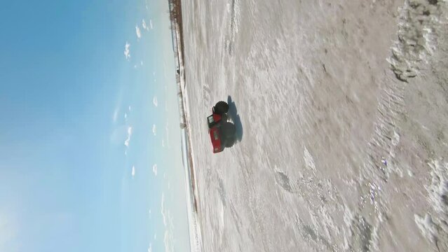 Arctic Rush. A car with large, low-pressure tires. Vertical 9x16 FPV Aerial Drone shot
