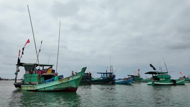 Traditional fishing boats moored on calm sea under overcast sky, depicting serene coastal livelihood, Phu Quoc, Vietnam