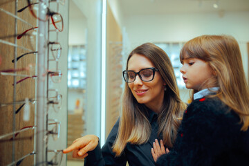 Mother and Daughter Choosing Eyeglasses Frames Together in a Store. Cheerful family looking for a...