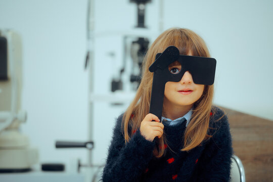 Little Patient Girl Holding a Lorgnette Pinhole occluder for Consultation