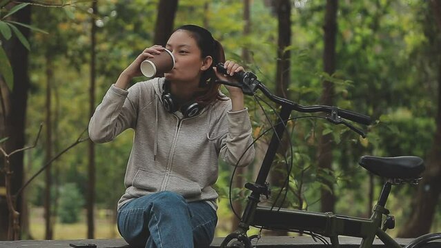 Chilling and relaxed young Asian woman in casual comfy clothes riding a bicycle on the bike lane in the park. hobby and exercise concept