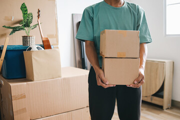 Close-up of a man holding stacked of carton boxes moving into new home.
