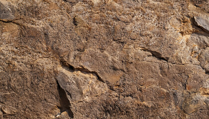 Naklejka premium Brown stone background. Rock texture. Mountain surface. Close-up. Stone wall. Wide banner with copy space for your design.