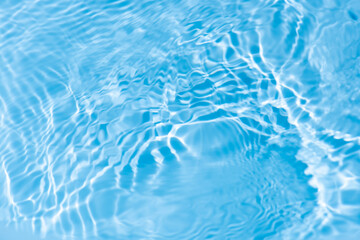 Water surface. Bluewater waves on the surface ripples blurred. Defocus blurred transparent blue colored clear calm water surface texture with splash and bubbles. Water waves with shining pattern.
