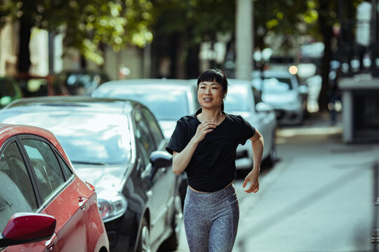 Young asian woman jogging on a sidewalk in the city