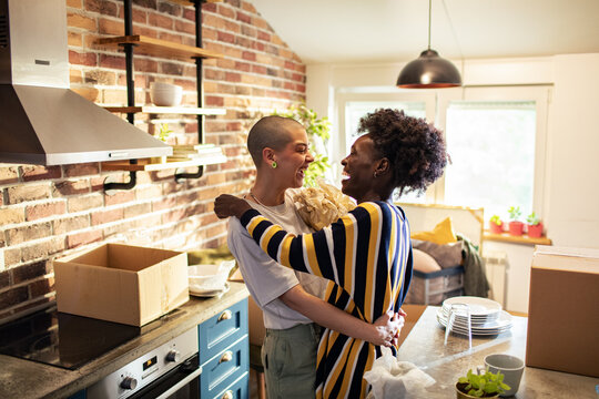 Smiling young lesbian lgbtqia couple moving in their new home