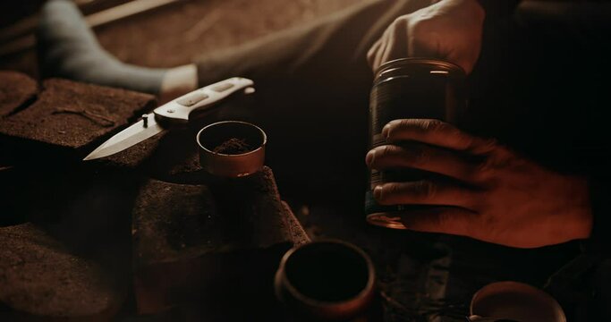 Campfire Coffee: Young homeless man putting coffee grounds into the metal filter of the old beat up moka pot he uses to brew his favourite baverage.