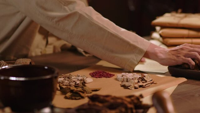 The physician is selecting each dry medicinal herb to package the medicine according to the prescription. Traditional Chinese medicine space.