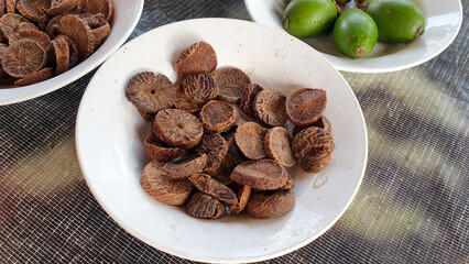 Close up of sliced dried betel nut, areca nut, on a white plate displayed at local market stall on island of New Guinea, West Papua, Indonesia