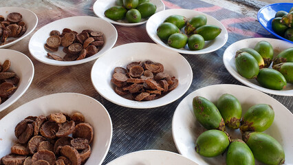 A selection of fresh and dried betel nut, areca nut, displayed in bowls at a local market stall in West Papua, Indonesia