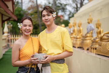 On Songkran Day, young Thai people wear Thai costumes to bathe Buddha statues and play on Songkran...