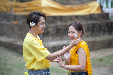 A beautiful Young Thai couple wearing Thai costumes playing in the water during Songkran in the...