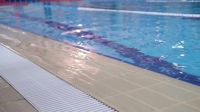 Calm water on empty swimming pool, dark lanes marks visible floor