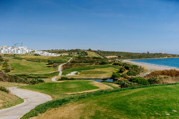 Sotogrande, Spain - January, 23, 2024 - A golf course with a curving path leads towards the sea,...