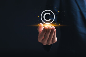 Copyright or patent concept, copyleft trademark license. Businessman holding virtual copyright symbol for author rights and patented intellectual property. - obrazy, fototapety, plakaty