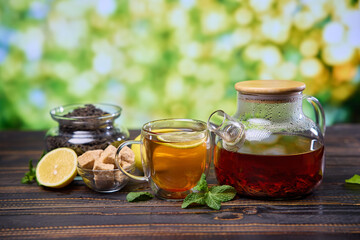 natural organic herbal tea in glass teapot and cup on a wooden table