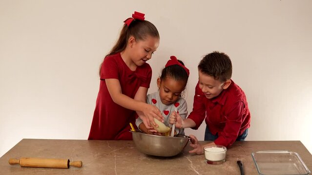 Niños felices amigos familia hermanos vestidos de rojo con corazones sobre mesa con rodillo amasando y preparando harinas masa para hornear galletas deliciosas leche mantequilla
