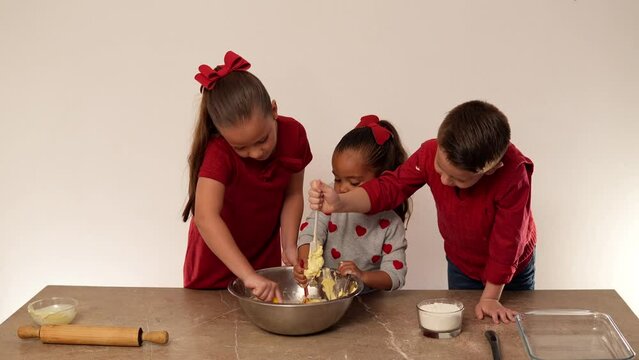 Ni&ntilde;os hermanos amigos felices preparando y mezclando mantequilla con harina para hacer unas ricas galletas y compartirlas con su familia ayudandose
