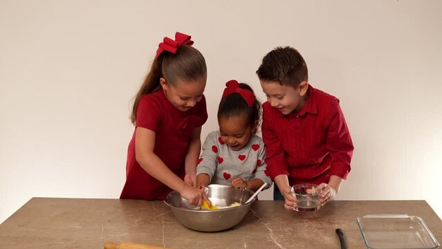 Ni&ntilde;os felices mezclando ingredientes para hornear y cocinar galletas en el d&iacute;a del amor y la amistad para compartir juntos con su familia delicioso postre