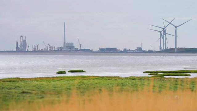 A city wrapped in haze and rotating wind turbines on the danish coast.