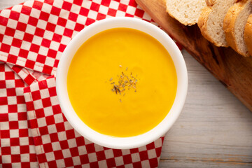 Homemade carrot and pumpkin cream soup. Easy, nutritious and healthy recipe. Served in a white bowl with bread croutons. Perfect to accompany everyday food.
