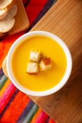 Homemade carrot and pumpkin cream soup. Easy, nutritious and healthy recipe. Served in a white bowl with bread croutons. Perfect to accompany everyday food.