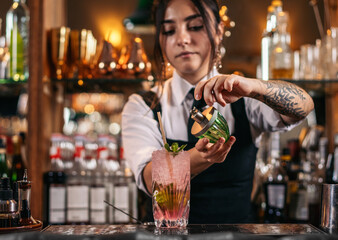 Female bartender preparing a cocktail in a traditional cocktail bar