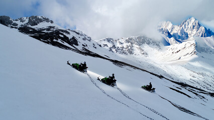 Adventurous team driving towards the summit on snowmobiles