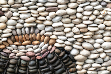 Nature-inspired, the art of decorative stones on the wall with white, brown, and black stones for the garden design.
