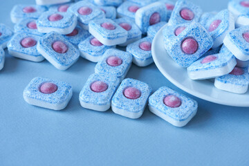 Obraz na płótnie Canvas Dishwasher tablets on a blue background. Use of dishwashing powder.