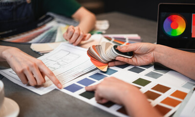 Close up hand choosing color from color sample swatch. The designer works with the customer and...