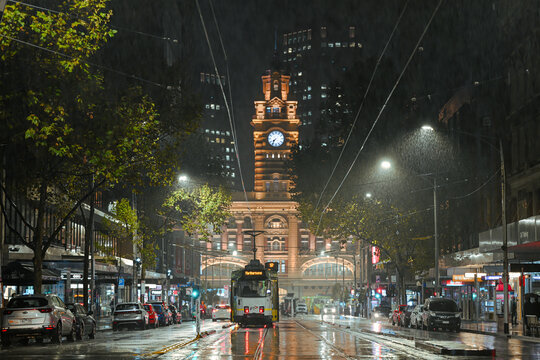 A tram in front of Flinders Street Train Station in Melbourne on a cold raining night. 