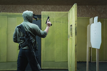 A man engages in tactical rifle and pistol shooting with nightvision at a shooting range. - obrazy, fototapety, plakaty